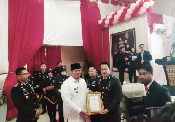Sekda Banyuasin Erwin Ibrahim didampingi Kapolres Banyuasin AKBP Risnan Aldino beserta jajaran saat memberikan Piagam Penghargaan untuk IPDA Ropiyan Anggono saat puncak perayaan HUT Bhayangkara ke-80 di Mapolres Banyuasin, Rabu (1/07/2026) ( Foto : Otaritanews@gmail.com/Irwan September)