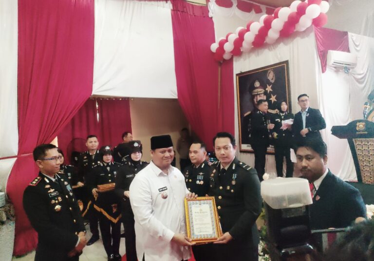 Sekda Banyuasin Erwin Ibrahim didampingi Kapolres Banyuasin AKBP Risnan Aldino beserta jajaran saat memberikan Piagam Penghargaan untuk IPDA Ropiyan Anggono saat puncak perayaan HUT Bhayangkara ke-80 di Mapolres Banyuasin, Rabu (1/07/2026) ( Foto : Otaritanews@gmail.com/Irwan September)